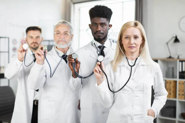 Medici multirazziali che tengono lo stetoscopio in mano nella stanza — Foto Stock