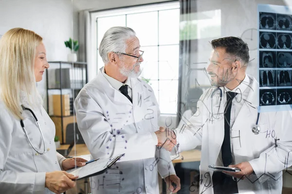 Experts en soins de santé en blouse de laboratoire serrant la main pendant la réunion — Photo