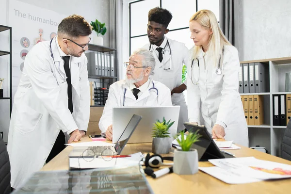 Médecin-chef âgé avec divers collègues sur la réunion — Photo