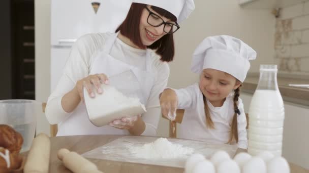 Menina bonito e sua bela mãe caucasiana estão polvilhando a massa com farinha — Vídeo de Stock