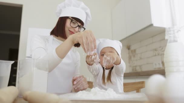 Χαρούμενη μαμά διασκεδάστε πασπαλίζοντας αλεύρι και ψήσιμο μπισκότα ή γλυκά με χαριτωμένο κορίτσι προσχολικής ηλικίας — Αρχείο Βίντεο