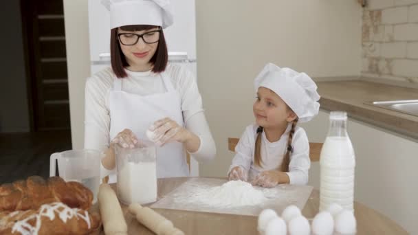 Семья проводит время вместе, разбивая яичную скорлупу и кладя яйца в муку во время выпечки пищи — стоковое видео