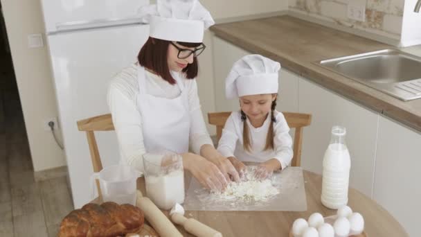 Дружелюбная молодая мать маленькая дочь готовить десерт пекарня на современной кухне месить тесто с руками — стоковое видео