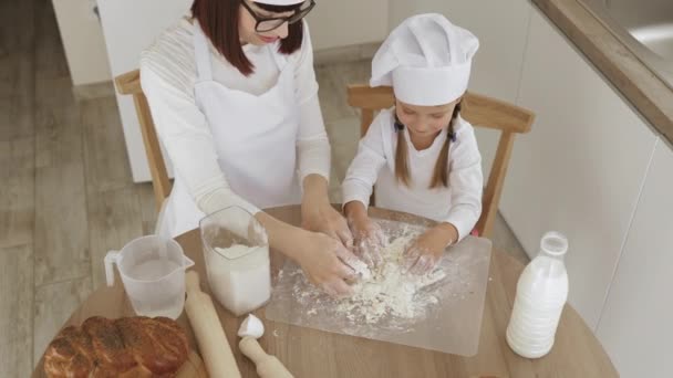 Bonito pequena criança caucasiana filha ajudando a mãe amassar preparando massa — Vídeo de Stock