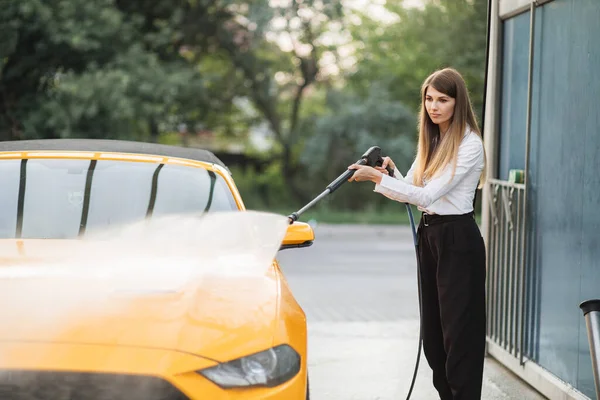 Başarılı iş kadını beyaz gömlek ve siyah pantolon giyiyor, sarı arabasını yıkıyor. — Stok fotoğraf