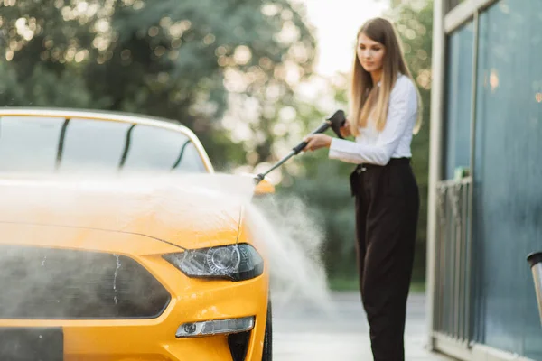 Beyaz gömlek ve siyah pantolon giyen neşeli iş kadını sarı arabasını yıkıyor. — Stok fotoğraf