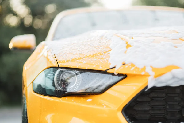 Tutup gambar horisontal lampu depan mobil kuning dengan busa bersih — Stok Foto