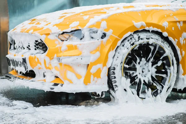 Przycięty obraz koła luksusowego żółtego samochodu w zewnętrznym samoobsługowej myjni samochodowej — Zdjęcie stockowe