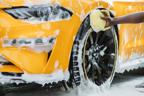 Czyszczenie nowoczesnych obręczy luksusowego żółtego samochodu w myjni samoobsługowej na zewnątrz. — Zdjęcie stockowe