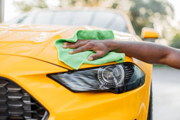 Imagen de primer plano de la mano del joven, lavado y limpieza de coches deportivos amarillos con paño de microfibra —  Fotos de Stock