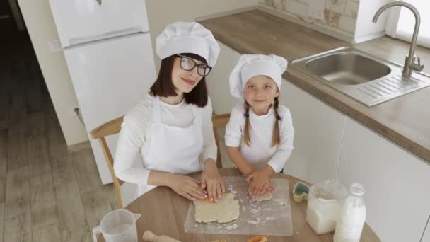 Szczęśliwa rodzina kaukaska cięcia surowego ciasta z plastikowymi przecinakami cookie patrząc w aparacie — Wideo stockowe
