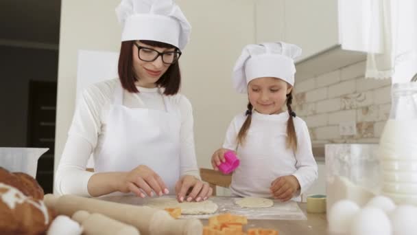 Petite fille utilisant des formes en plastique pour couper la pâte — Video
