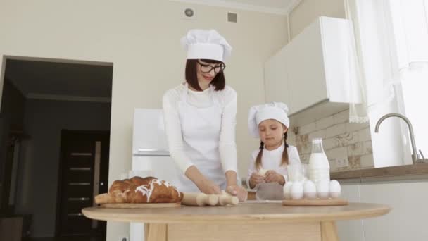 Caucásico madre e hija hornear juntos hacer masa y utilizar los ingredientes necesarios para ello. — Vídeos de Stock