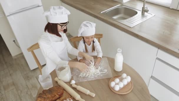 Felice madre e le sue figlie in cappelli di chef e grembiule bianco facendo pasta per la cottura — Video Stock