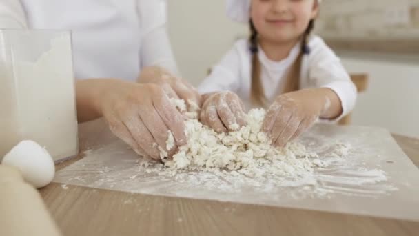 画像を閉じます女性と小さな娘は小麦粉で粉末木製のテーブルと生地をこねる — ストック動画