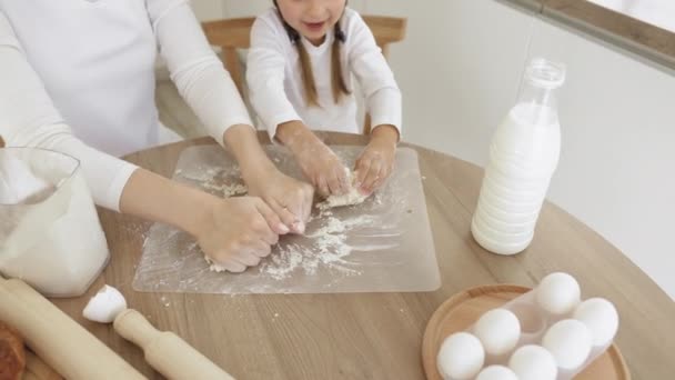 Cerrar imagen mujer e hija pequeña amasan masa con las manos mesa de madera en polvo con harina — Vídeos de Stock