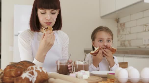 Nahaufnahme von Mädchen und Mutter essen Croissants und trinken Kakao mit Marshmallows — Stockvideo