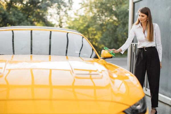 정장, 셔츠, 바지를 입은 젊은 여자가 자동차 백미러를 청소하는 모습 — 스톡 사진