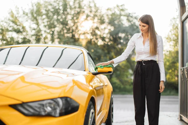 Wanita muda dalam pakaian bisnis, kemeja dan celana membersihkan kaca spion mobil — Stok Foto