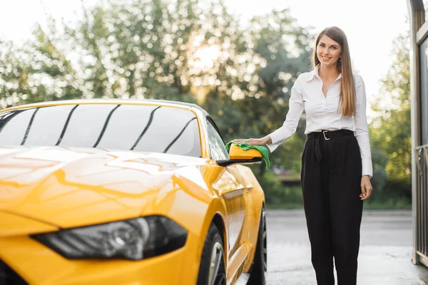 Wanita bisnis yang mengenakan kemeja putih dan celana hitam menyeka kaca spion mobil — Stok Foto