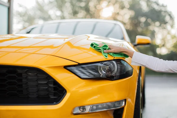 İş kadını mikrofiber bezle sarı spor arabayı yıkıyor ve temizliyor. — Stok fotoğraf