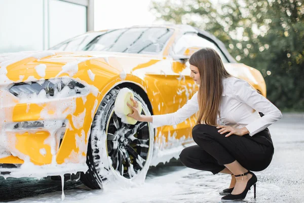 Atrakcyjna kobieta nosząca służbowy wygląd koło myjące, felgi samochodowe — Zdjęcie stockowe