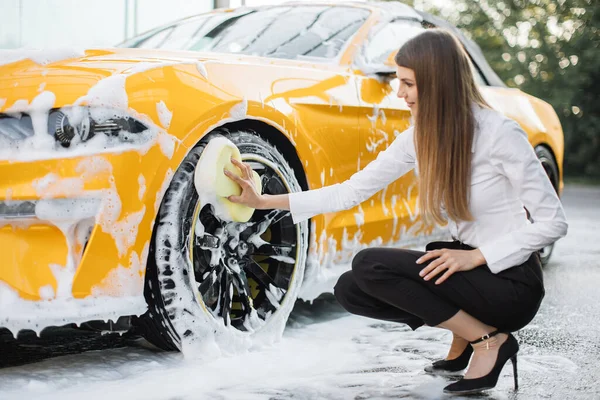 Atrakcyjna kobieta nosząca służbowy wygląd koło myjące, felgi samochodowe — Zdjęcie stockowe