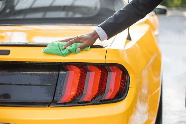 Zbliżenie przycięty obraz dłoni młodego afrykańskiego biznesmena, mycie i czyszczenie żółty samochód sportowy — Zdjęcie stockowe