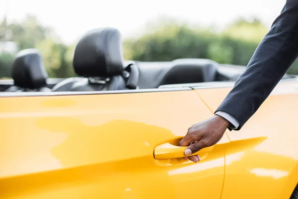 Hand afrikansk man i kostym på handtag av modern gul cabrilet bil. — Stockfoto
