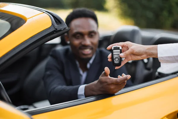 Kvinnlig auto säljare ger nycklar till manliga kunden bildar sin nya sportbil. — Stockfoto
