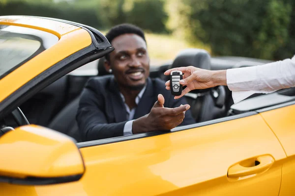 Kvinnlig auto säljare ger nycklar till manliga kunden bildar sin nya sportbil. — Stockfoto