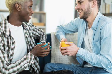 İki sevecen adam çay içip kanepede konuşuyor.