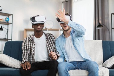 Evde boş zamanlarında VR gözlük takan aynı cinsiyetten çift.