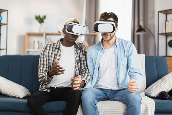 Multiculturális meleg pár VR headsettel a kanapén ülve — Stock Fotó