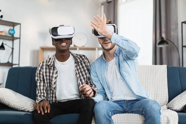 Evde boş zamanlarında VR gözlük takan aynı cinsiyetten çift.