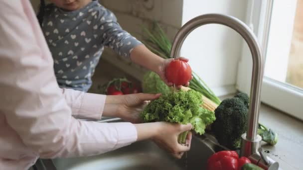 Nahaufnahme der jungen schönen Mutter im Hijab und ihrer niedlichen kleinen Tochter beim Gemüsewaschen — Stockvideo