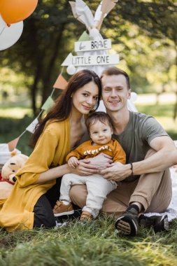 Çadır çadırında poz veren sevimli oğlu olan mutlu genç ebeveynler.