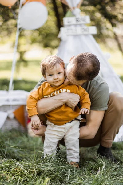 Cuidar do pai abraçando e beijando o pequeno filho no ar fresco — Fotografia de Stock