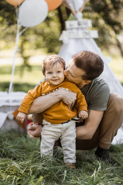 Cuidar do pai abraçando e beijando o pequeno filho no ar fresco — Fotografia de Stock