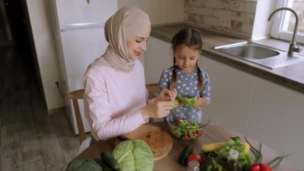 Mãe muçulmana e sua filha cozinhar na cozinha preparando salada de comida juntos — Vídeo de Stock