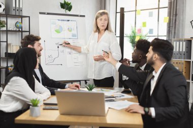 Çeşitli şirket çalışanlarının konferansını yöneten yaşlı kadın.