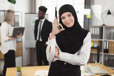 İş arkadaşlarıyla ofiste poz veren tesettürlü kadın
