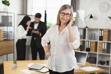 Ofiste cep telefonundan konuşan Kafkas kıdemli kadın.