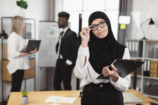 Жінка в хіджабі і окулярах тримає кишеню під час зустрічі — стокове фото