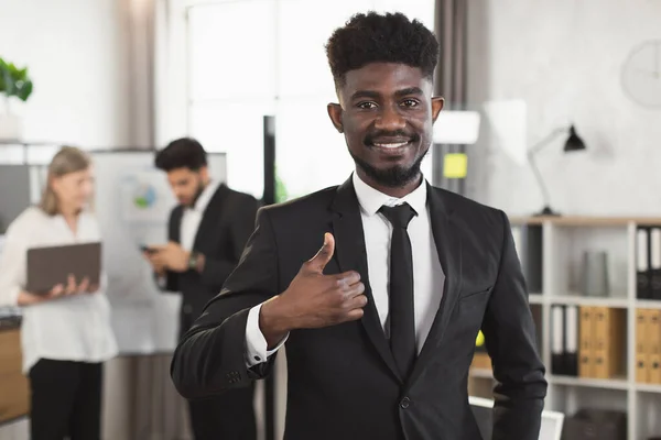 Un homme d'affaires africain prospère souriant à la caméra au bureau — Photo