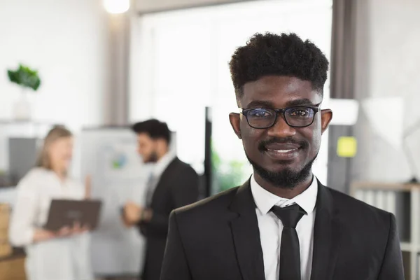 Homme d'affaires africain en costume et lunettes posant au bureau — Photo