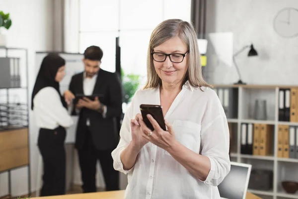 Femme d'affaires avec les cheveux gris en utilisant mobile au bureau — Photo