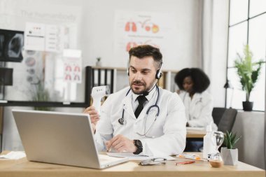 Video çağrısı sırasında elektronik termometreyi gösteren doktor