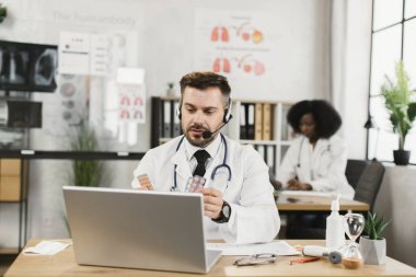Kulaklıklı doktor iş arkadaşlarıyla online toplantı yapıyor.