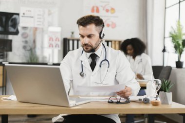 Kulaklıklı doktor iş arkadaşlarıyla görüntülü görüşme yapıyor.